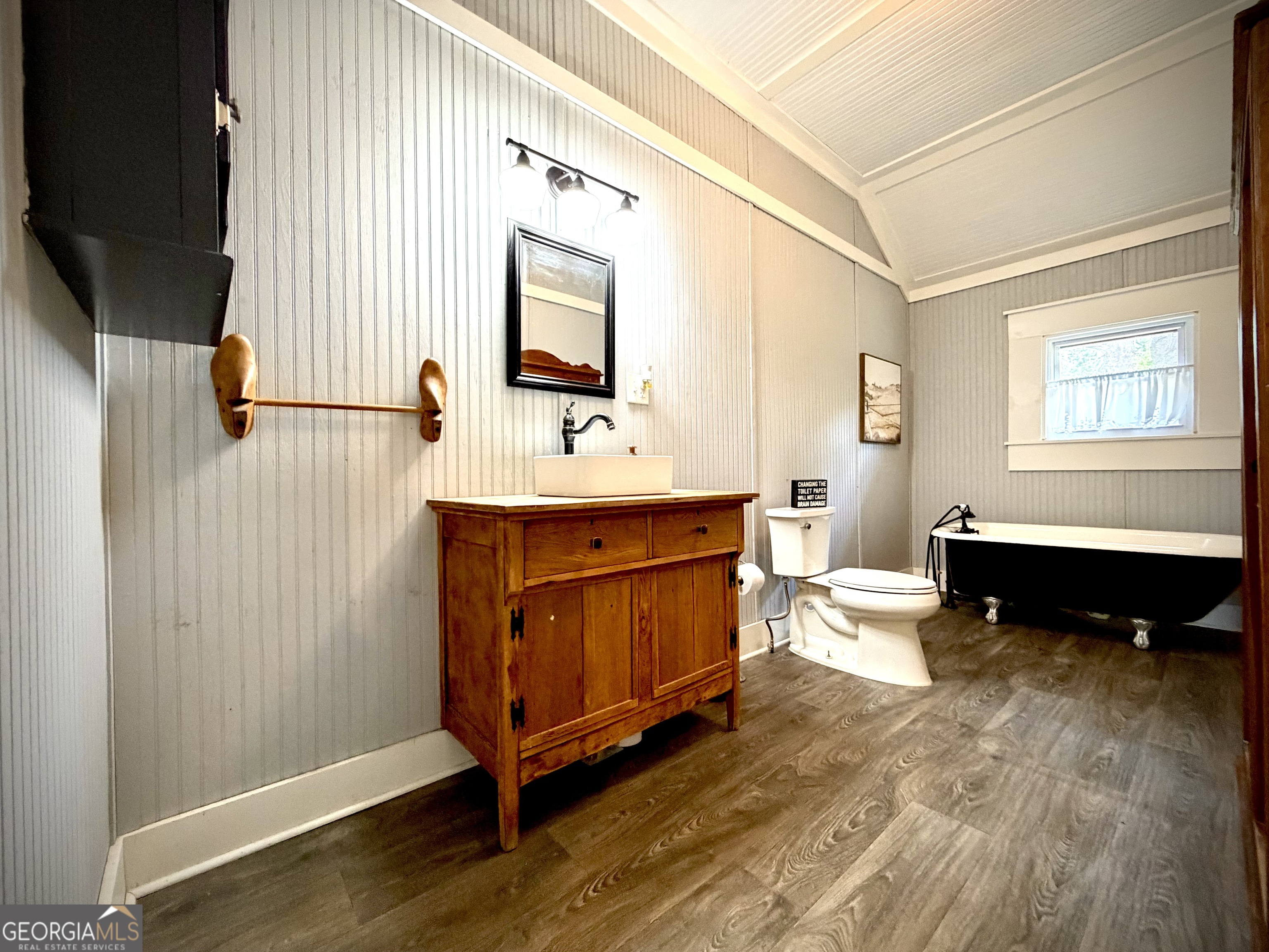 Bathroom with a rustic wood vanity, white vessel sink, and black-and-white clawfoot tub.