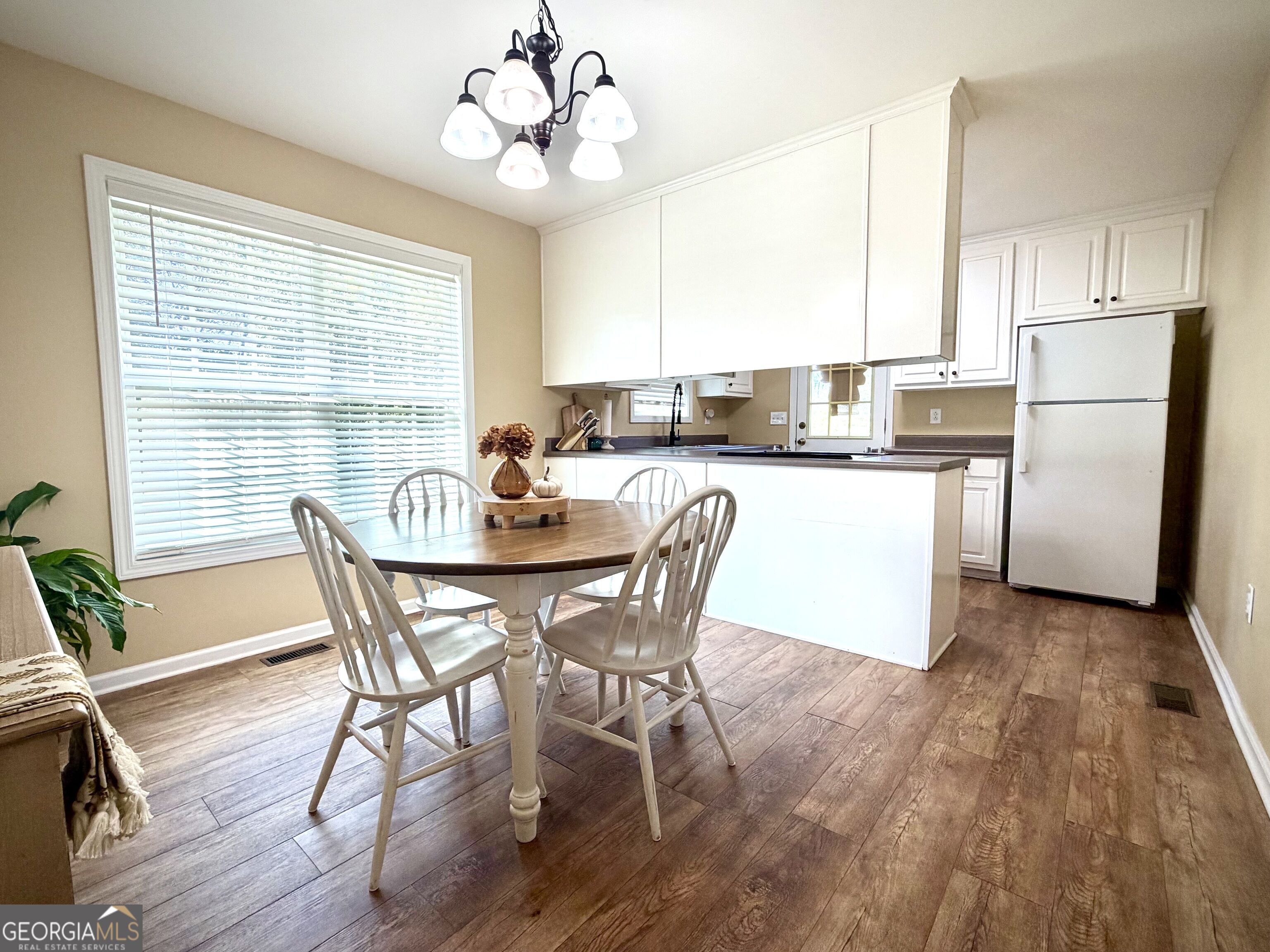 Kitchen and dining area with white cabinetry, a peninsula, and a round table beside a large window.