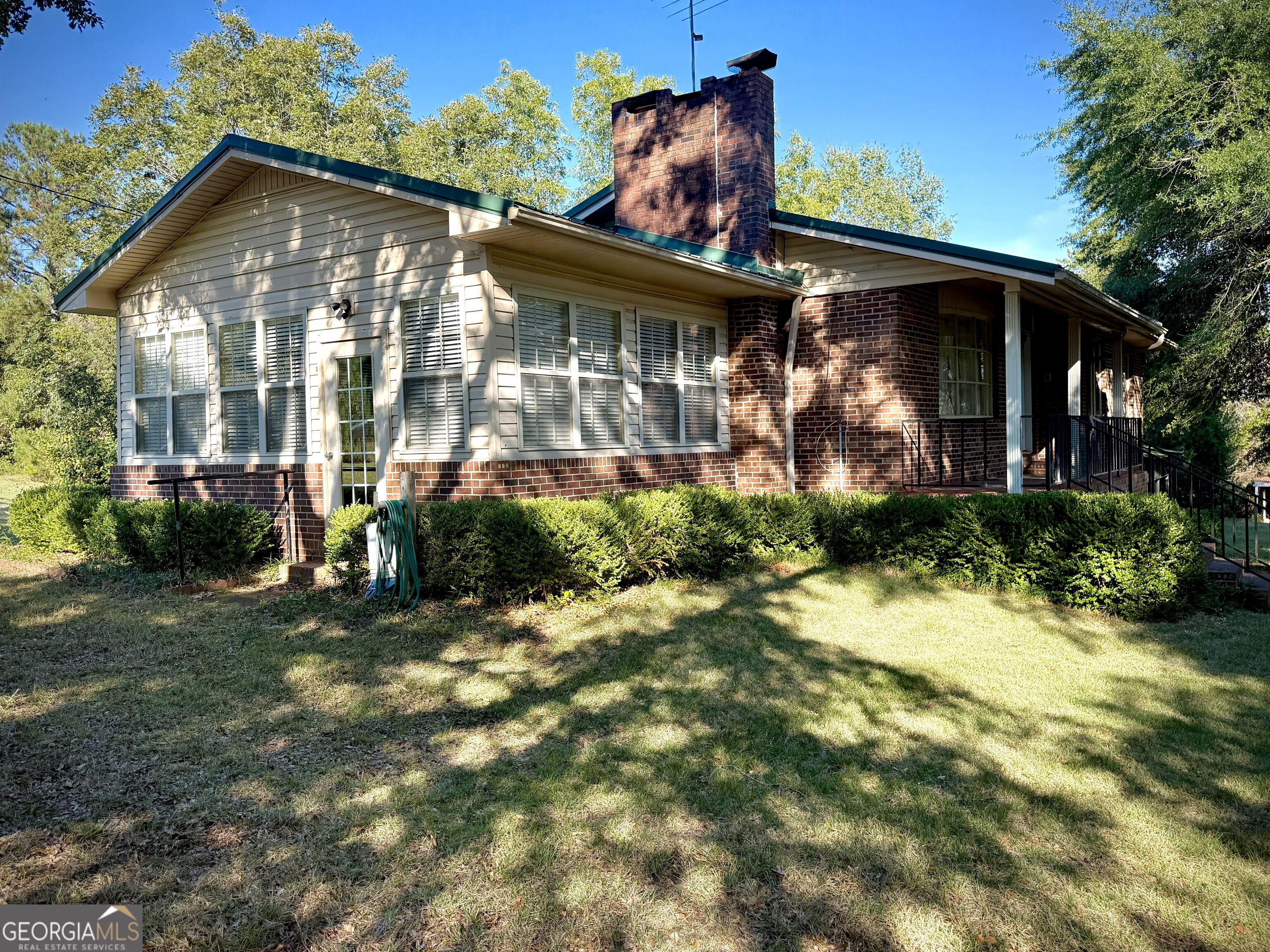 Single-story brick-and-siding home with a tall chimney, shuttered windows, and covered porch.
