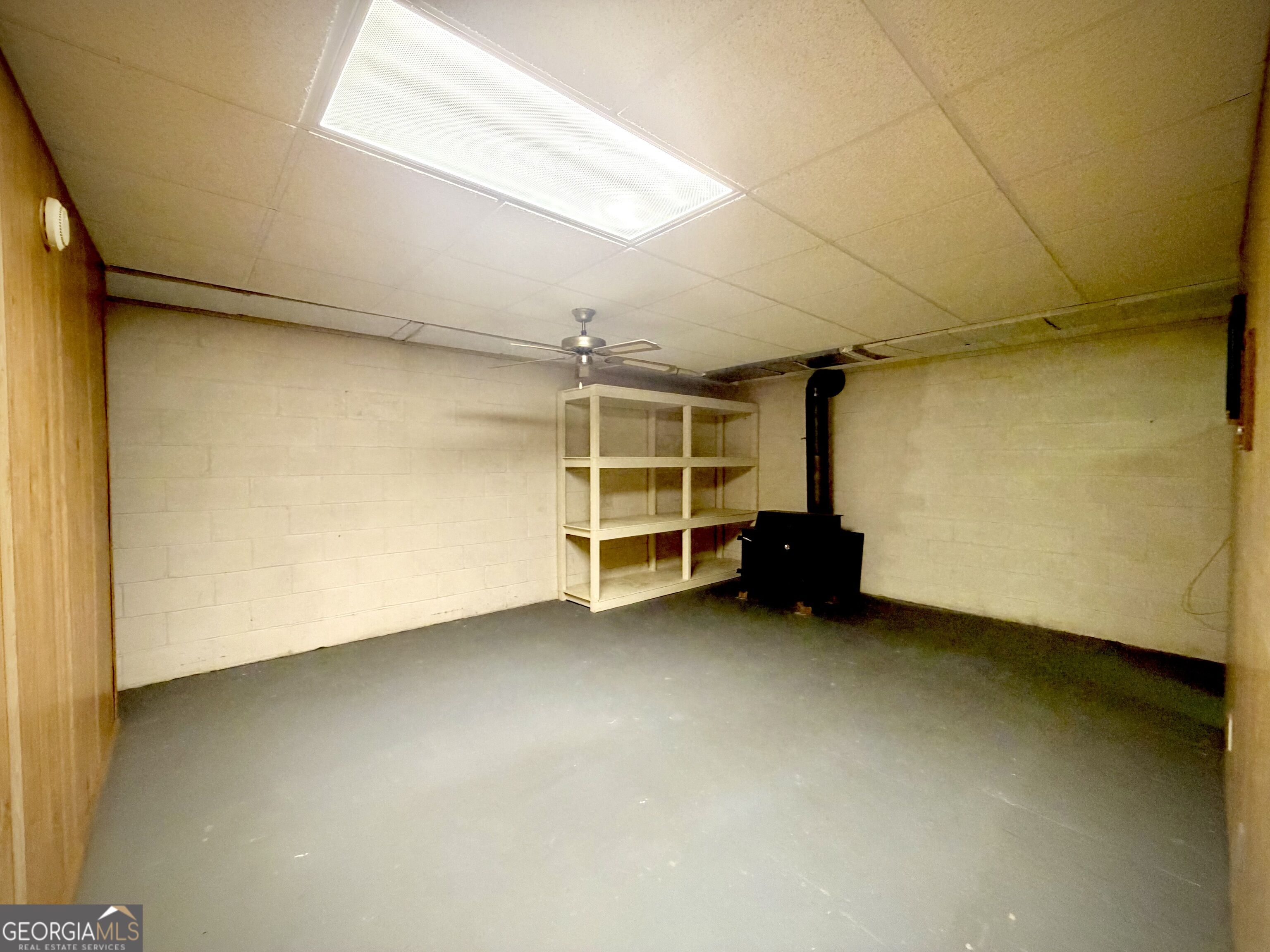 Unfinished workshop with open shelving and a black wood stove