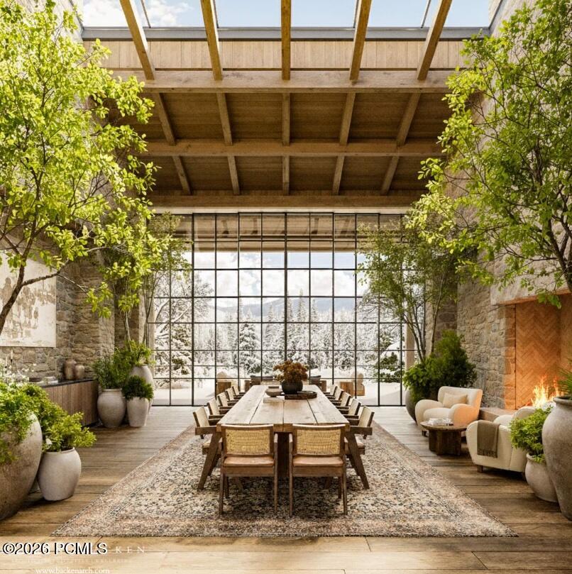 Dining room with a long wooden table, timber ceiling, snowy views, and an adjoining fireplace sitting area.
