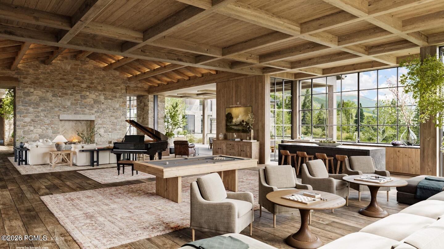 Furnished great room with timber beams, stone fireplace, grand piano, and mountain views through tall windows.