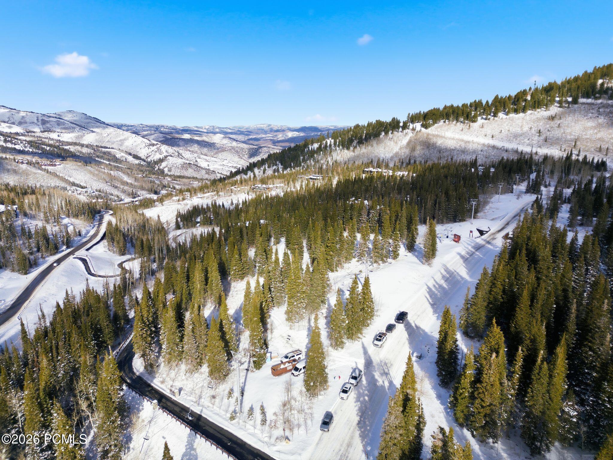 Aerial view of snow-covered roads and evergreen forest across a mountain neighborhood.