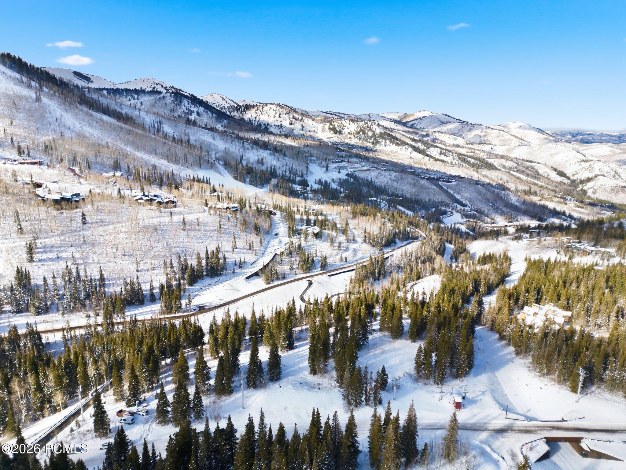 Aerial view of a snowy mountain community with winding roads, scattered homes, and evergreen forest.