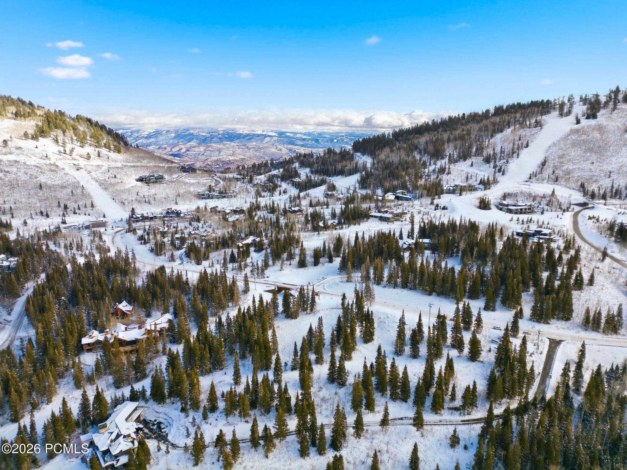 Snow-covered mountain neighborhood with scattered homes, winding roads, and evergreen trees.