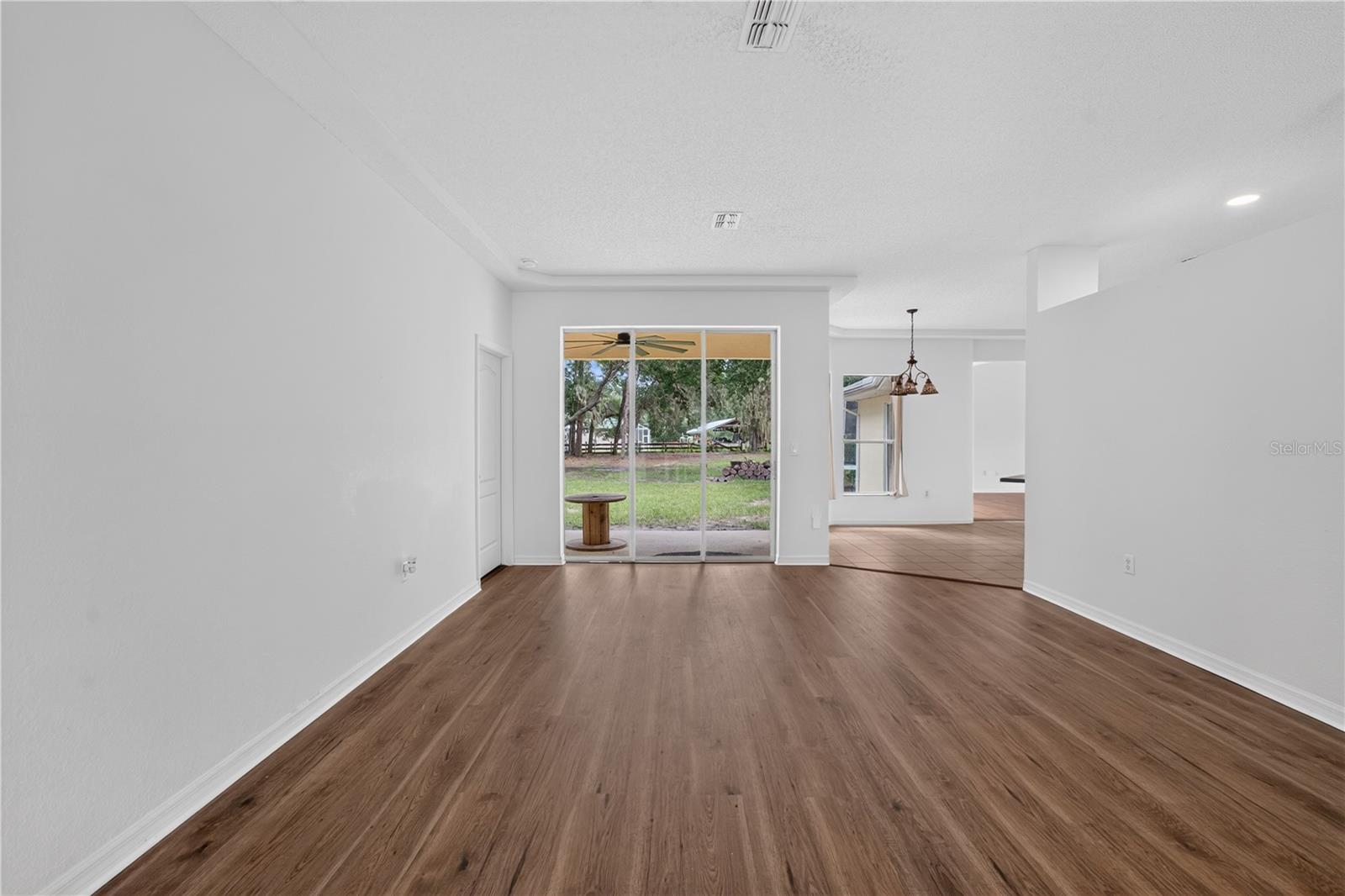 Vacant living room with wood-look floors and sliding glass doors to the backyard.