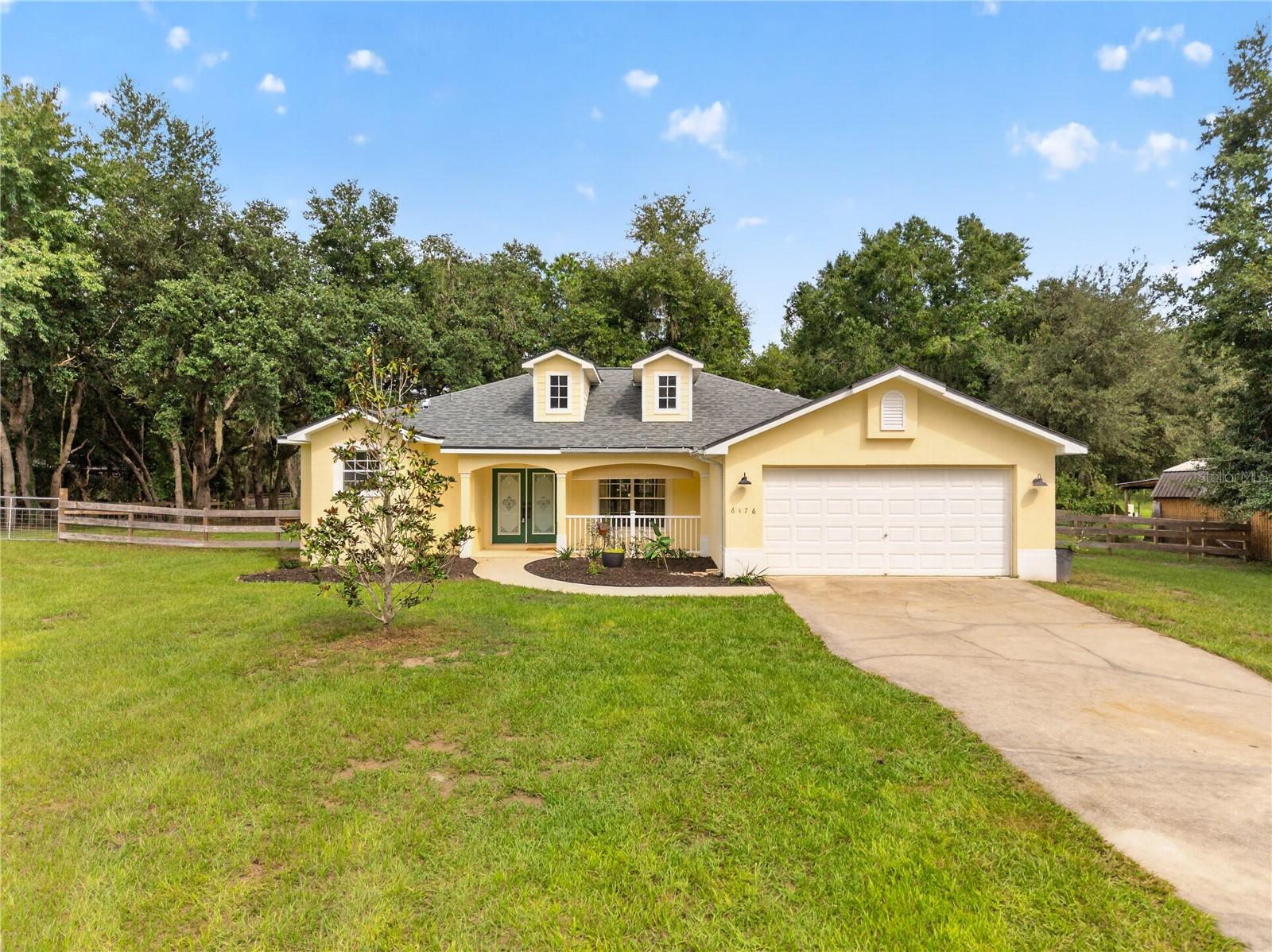 Yellow single-story home with a covered porch, two roof dormers, and an attached garage.