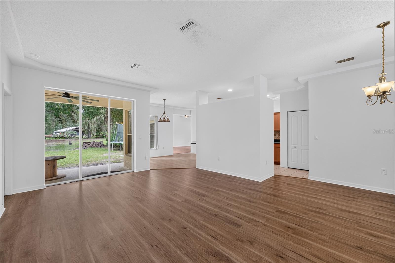 Unfurnished living room with wood-look floors and sliding glass doors to a covered patio.