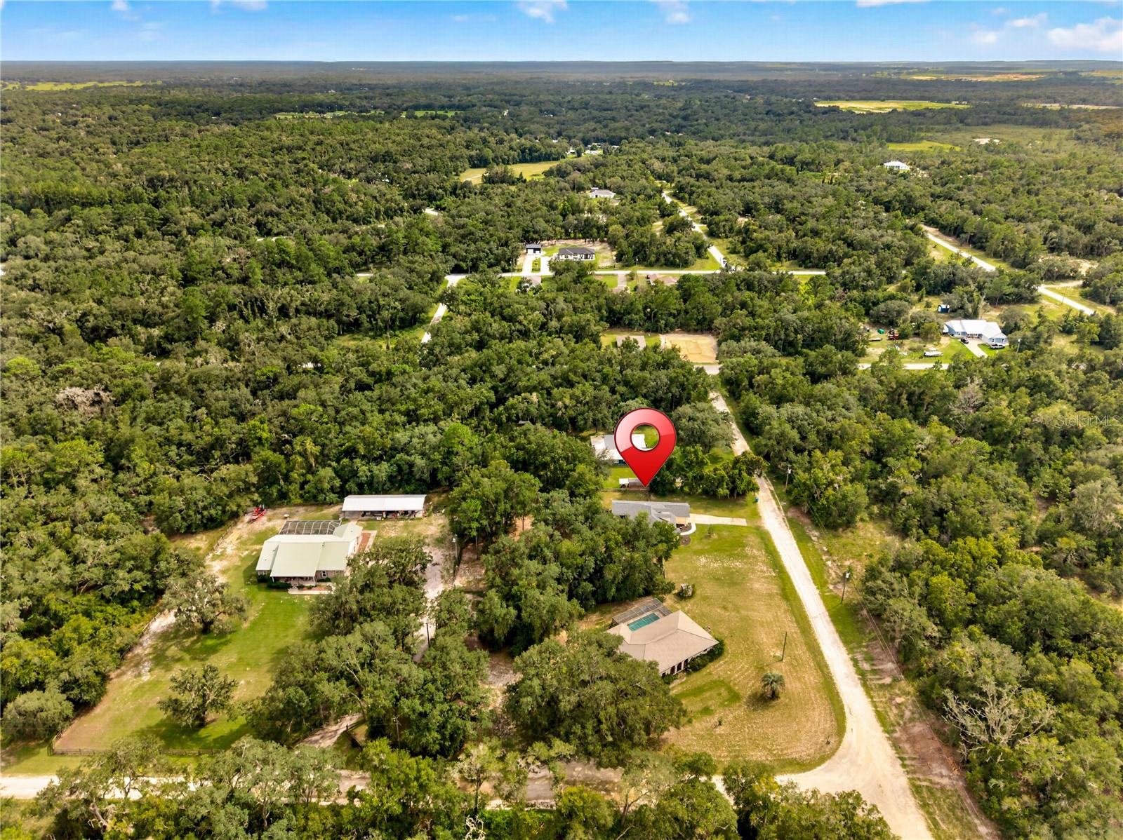 Aerial view of the marked property amid dense woodland and scattered homes along rural roads.
