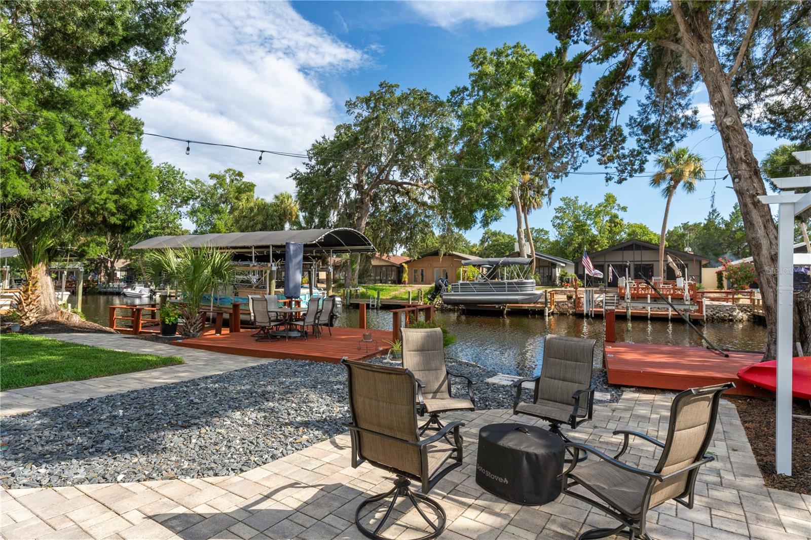 Waterfront patio with outdoor seating overlooking a canal, private docks, and covered boat lifts.