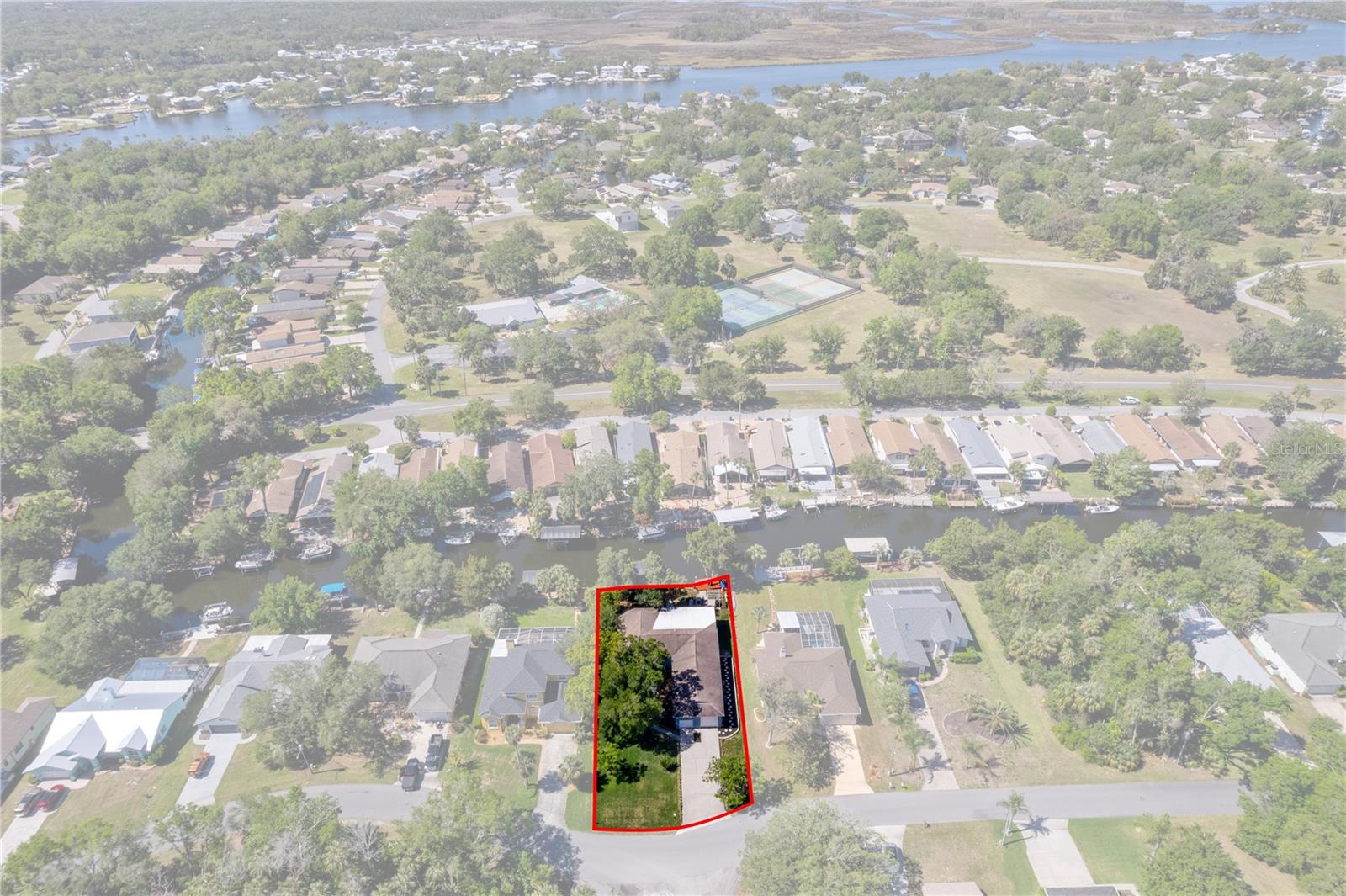 Aerial view of a red-outlined waterfront property beside a canal in a residential neighborhood.