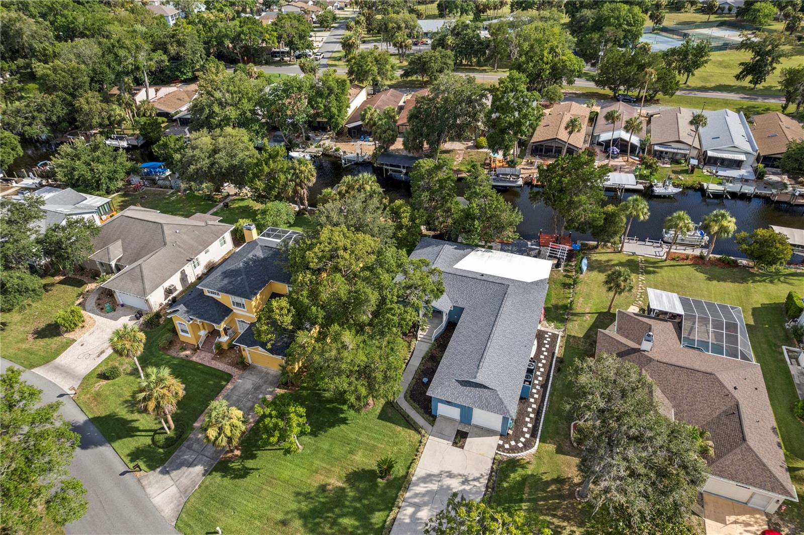 Aerial view of canal-front homes, private docks, and a tree-lined residential neighborhood.