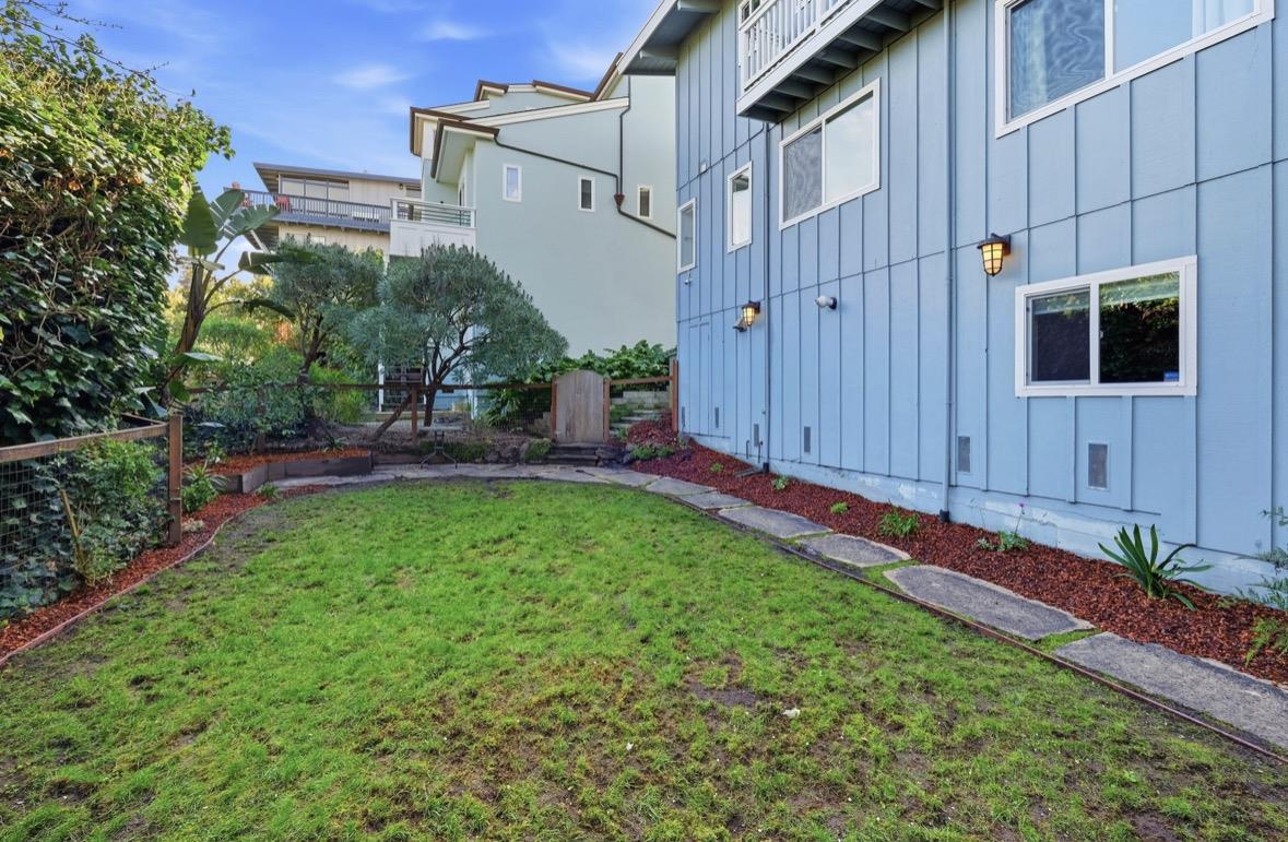 Side yard with a lawn, stepping-stone path, landscaped borders, and blue-sided home.