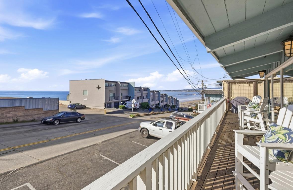 Oceanfront balcony with white railing and outdoor seating overlooking the beach and ocean.