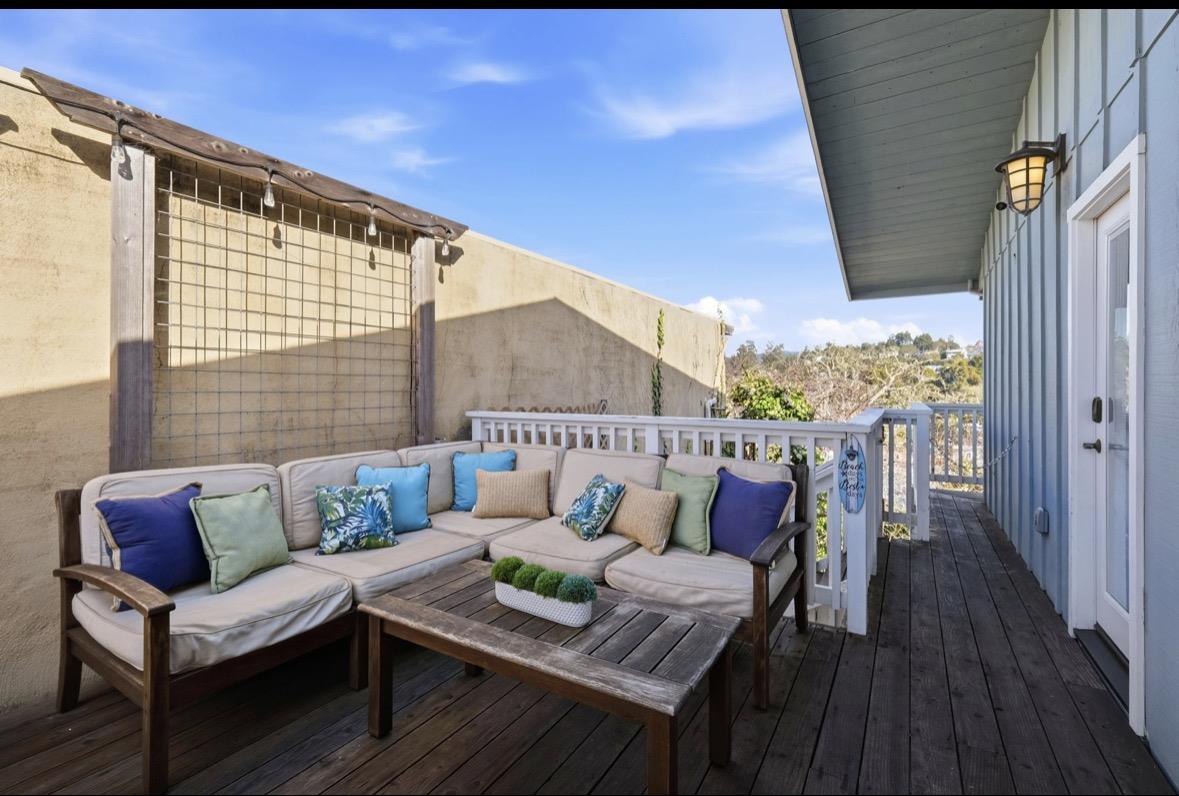 Outdoor deck with a cushioned sectional sofa and coffee table beside a white railing.