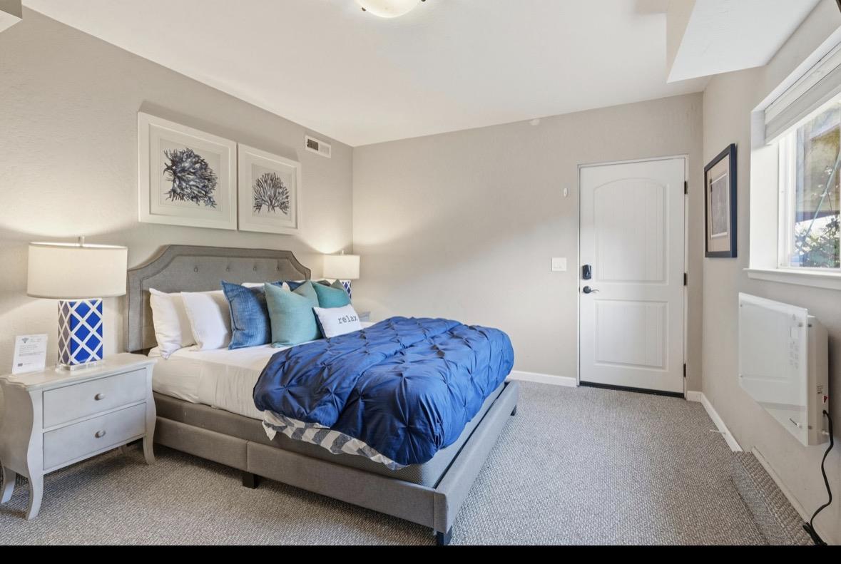 Staged bedroom with a gray upholstered bed, vivid blue comforter, and matching blue-and-teal accents.
