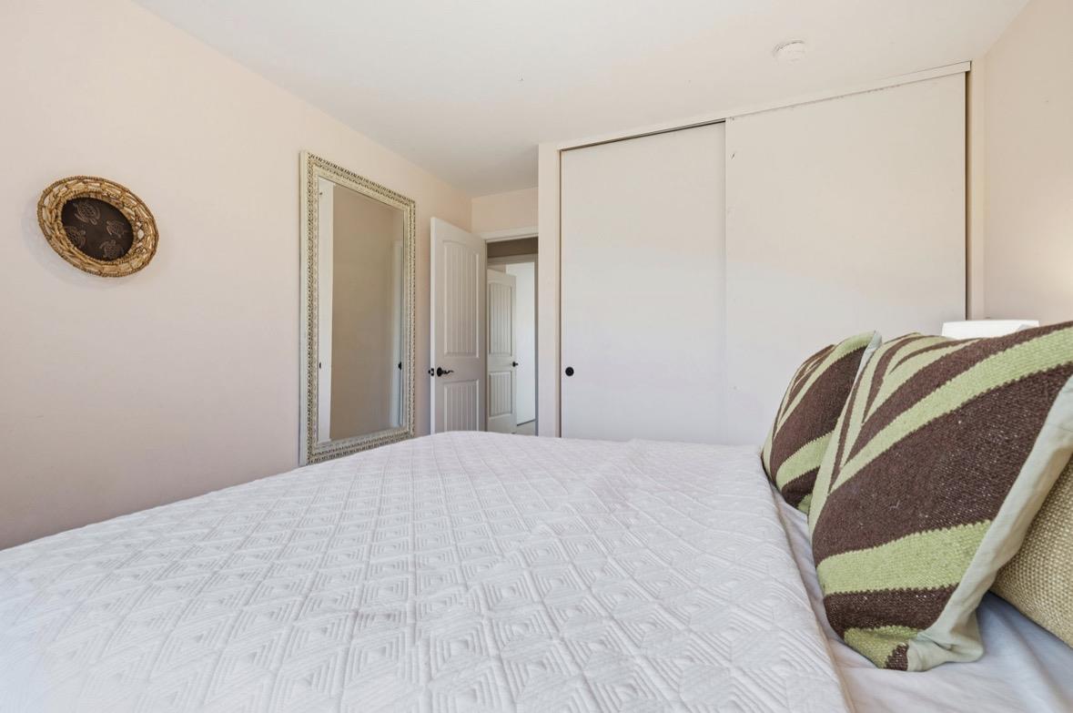 Bedroom with a white quilted bed, striped pillows, and sliding closet doors.