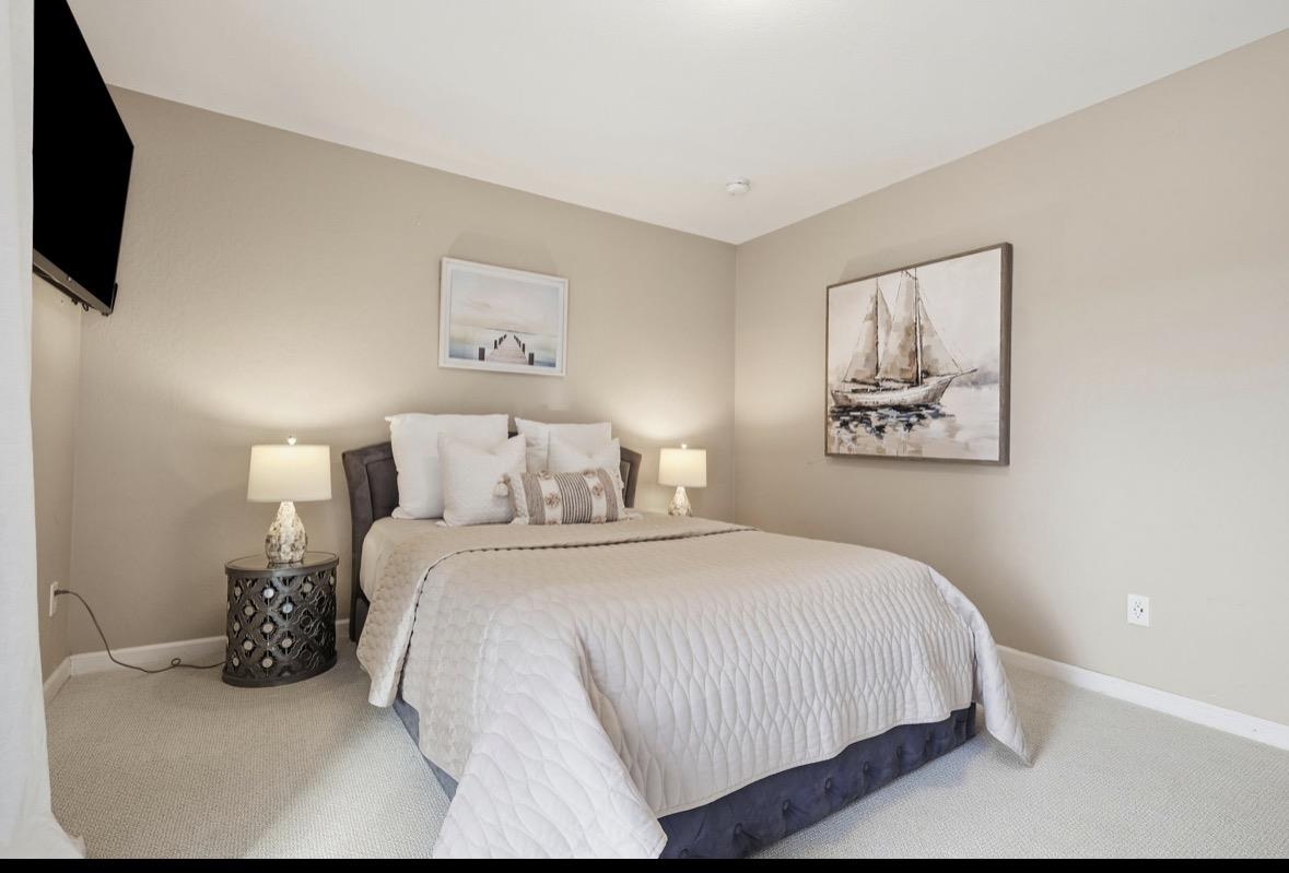 Staged bedroom with a white quilted bed, matching bedside lamps, and sailboat artwork.