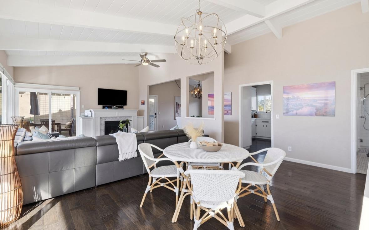 Open-plan living and dining area with a dark sectional, white dining set, fireplace, and patio doors.