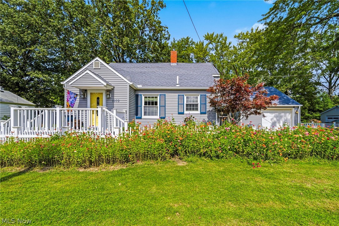 Gray single-story home with blue shutters, a yellow front door, and flower beds.