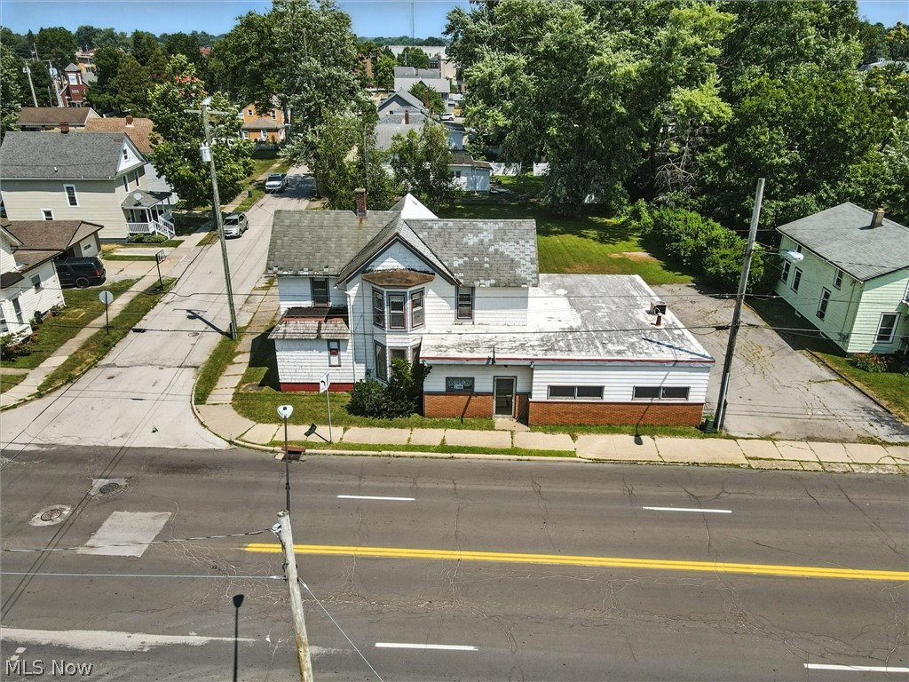 Corner building with a white upper facade, brick base, and streets on two sides.