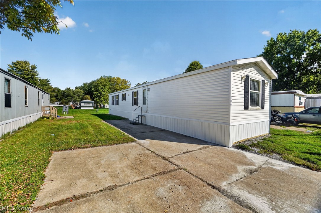 White manufactured home beside a concrete driveway in a residential community.