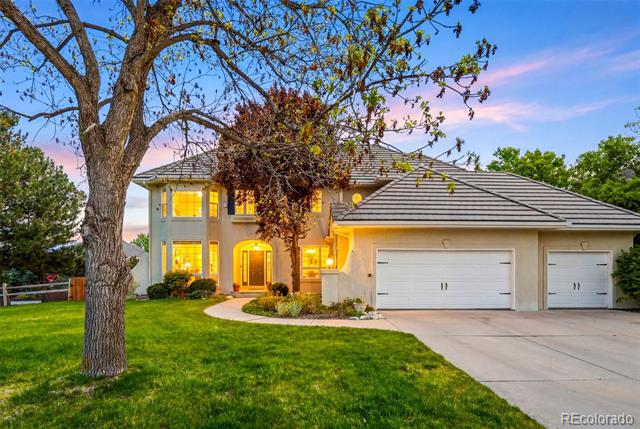 Two-story house with a gray tile roof, lit windows, and an attached garage at dusk.