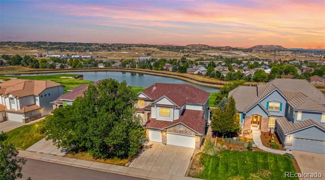 Aerial view of suburban homes and green lawns beneath a pink dusk sky.