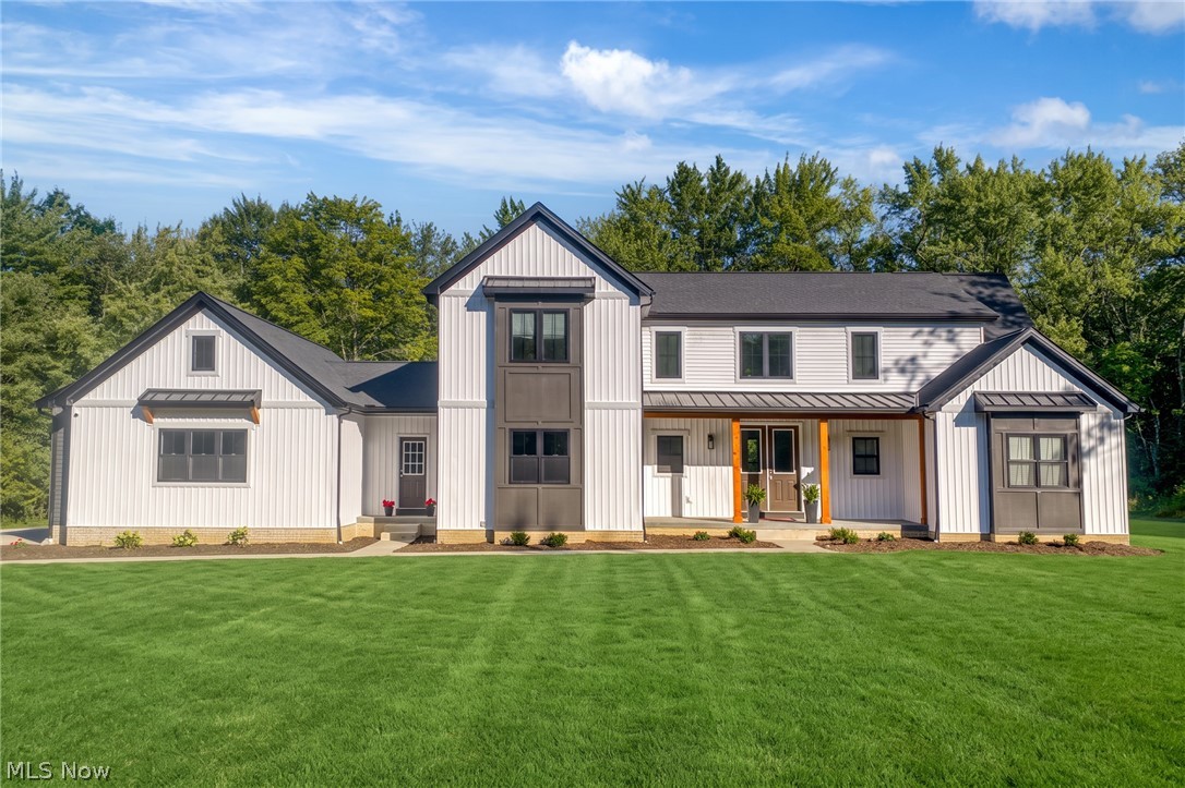 White modern farmhouse with multiple gables, broad green lawn, and mature trees.