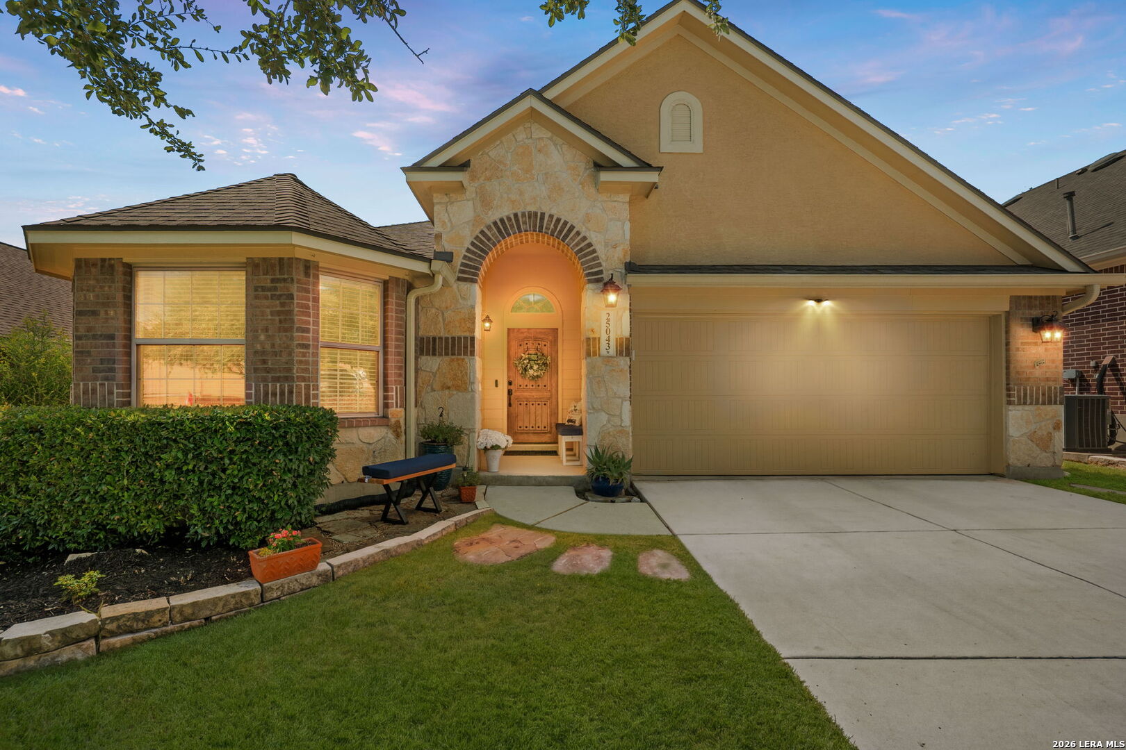 Front exterior of a stone-and-brick home with an arched entry and attached two-car garage.