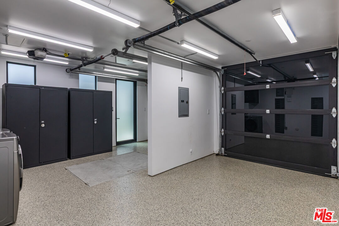 Modern garage with speckled flooring, tall black storage cabinets, and a dark sectional overhead door.