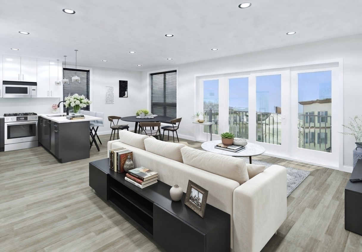 Open-plan living room and kitchen with a dark island and large glass balcony doors.