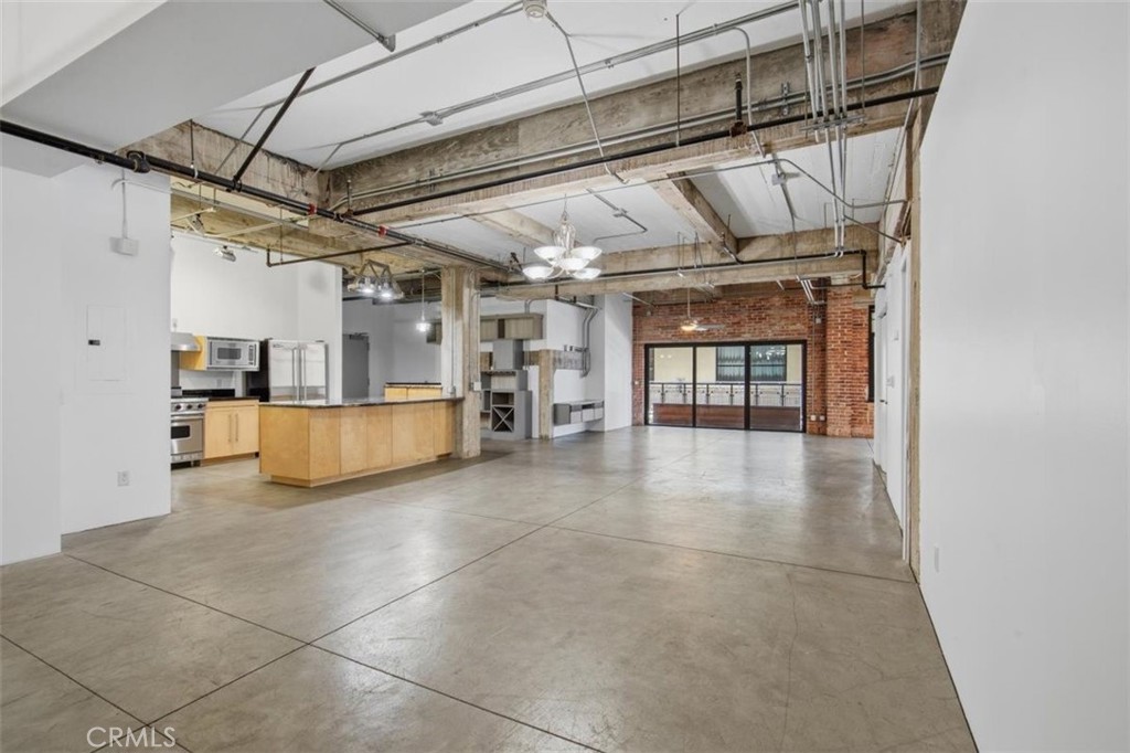Open loft interior with exposed beams, concrete floors, and a kitchen island.