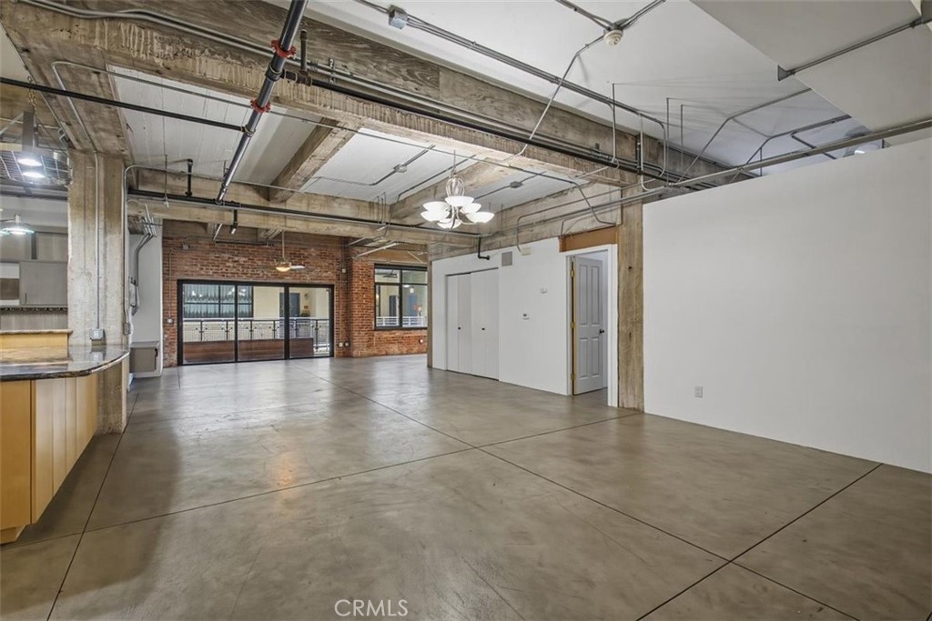 Open loft interior with polished concrete floors, exposed brick, industrial ceiling beams, and a counter.