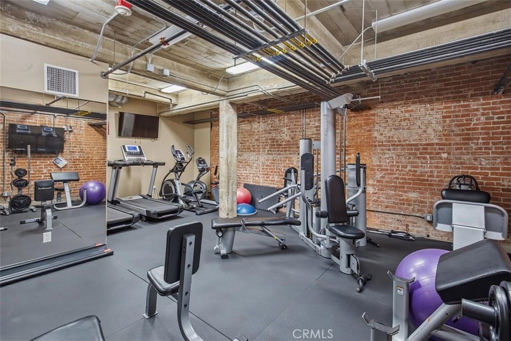 Fitness center with exercise machines, treadmills, and exposed brick walls.