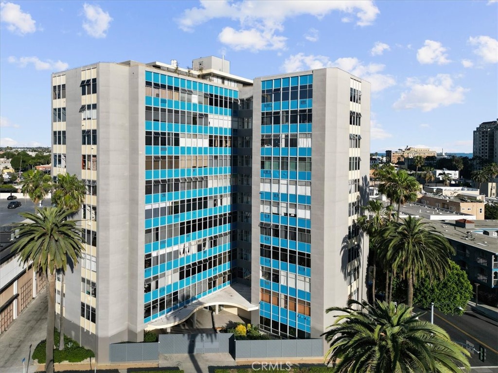 Multi-story building with blue window bands and palm trees along the surrounding streets.