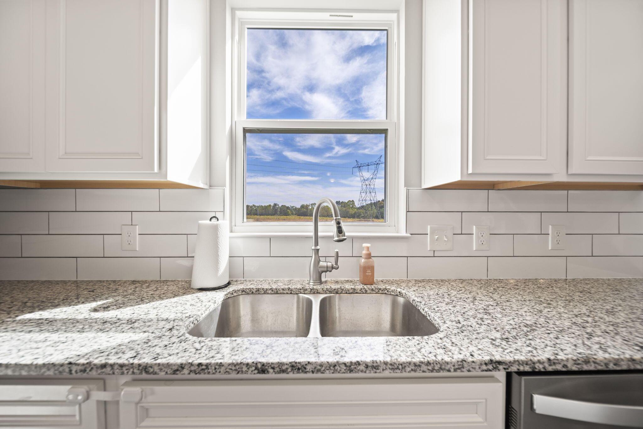 Kitchen sink with granite counters and a window overlooking a power transmission tower.