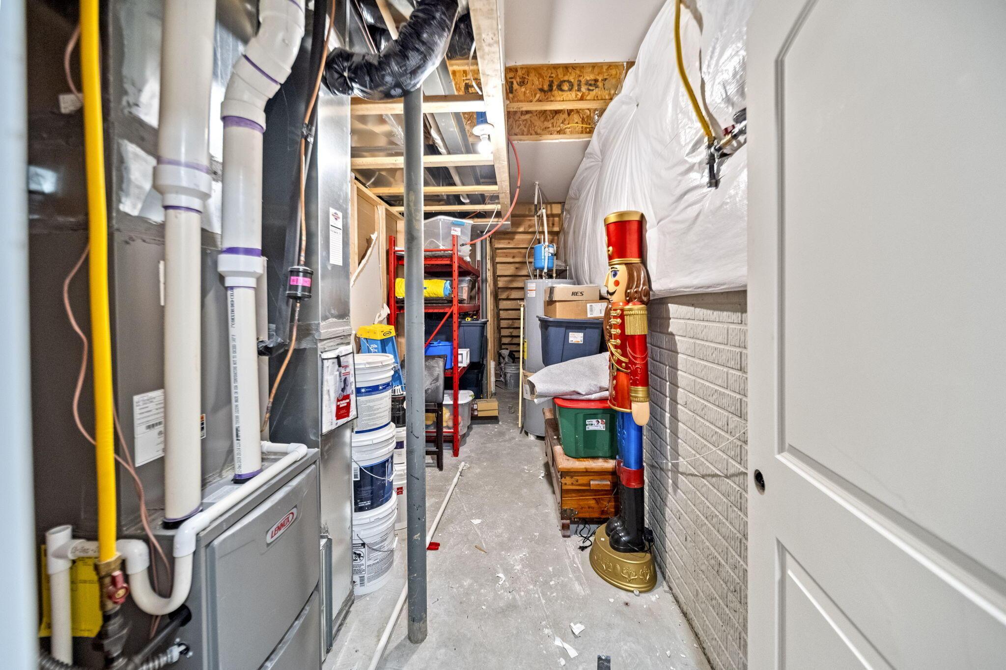 Basement utility and storage area with exposed pipes, shelving, bins, and a red-and-gold nutcracker.