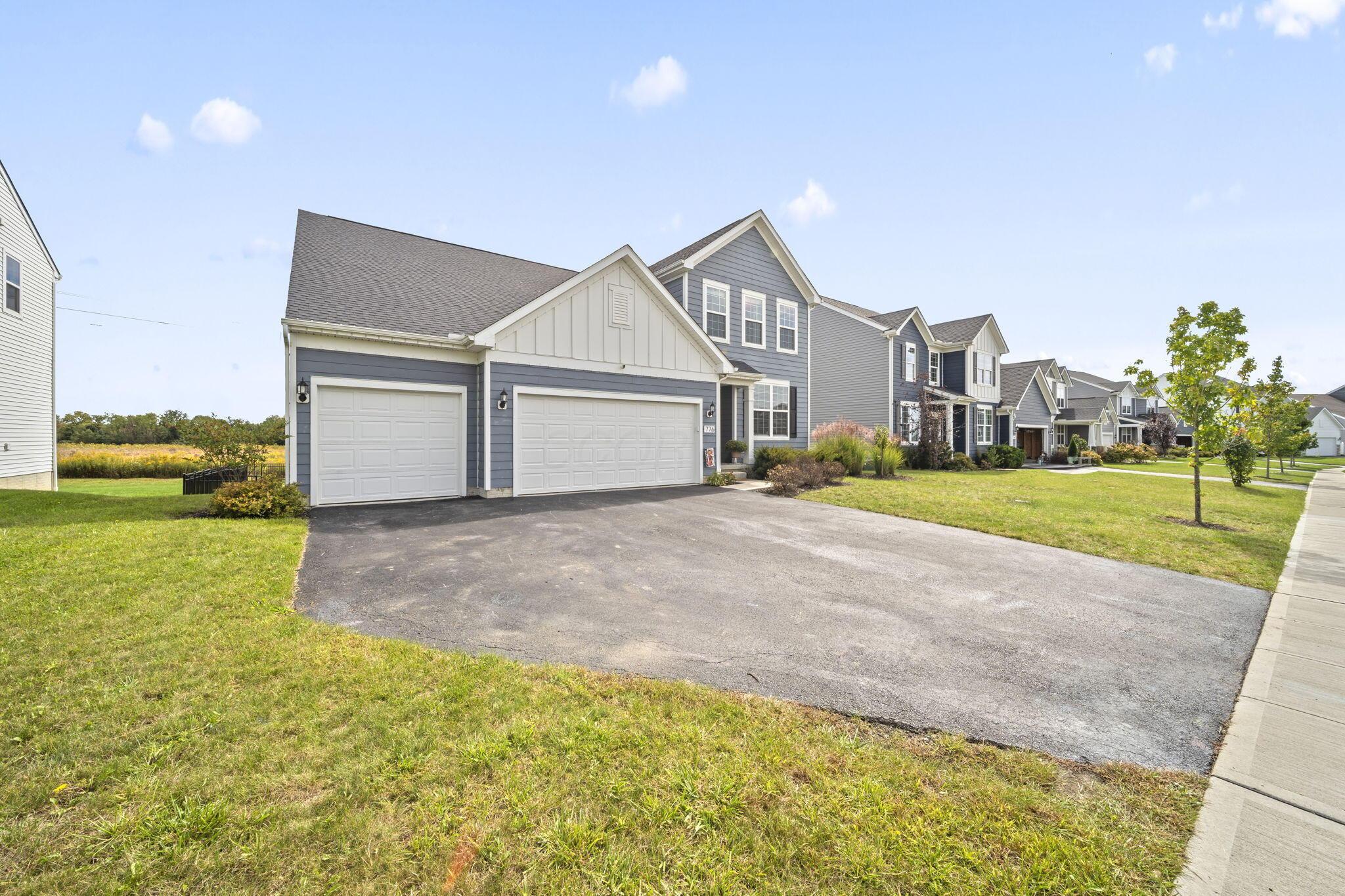 Blue-gray two-story home with two garage doors and a wide driveway.