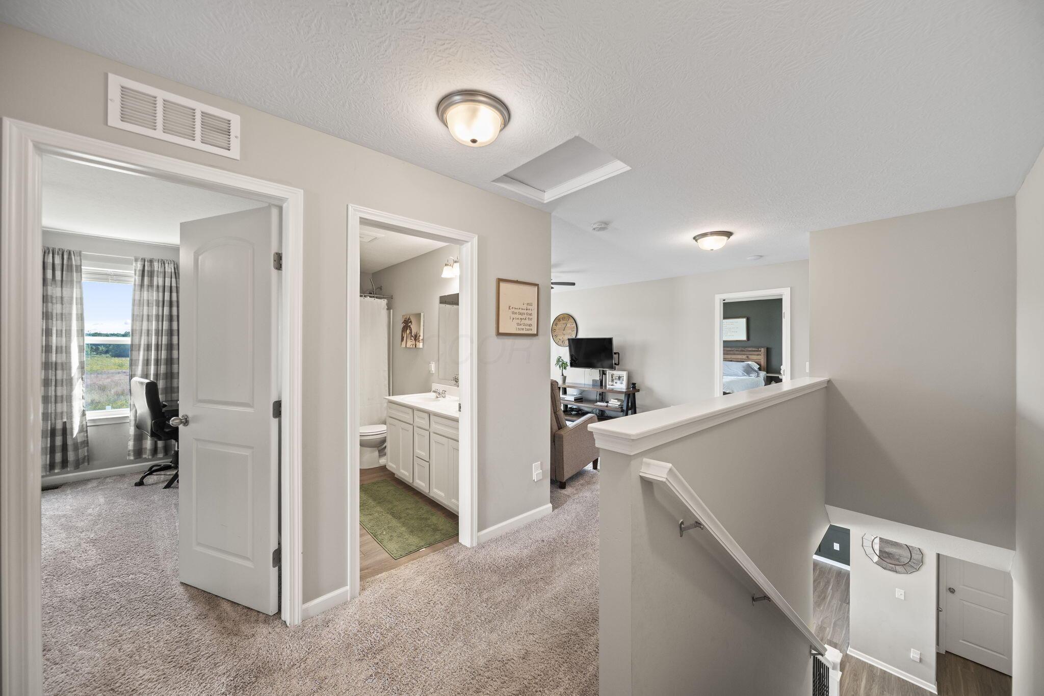 Upstairs landing overlooking the stairs, with doorways to a bathroom and carpeted bedrooms.