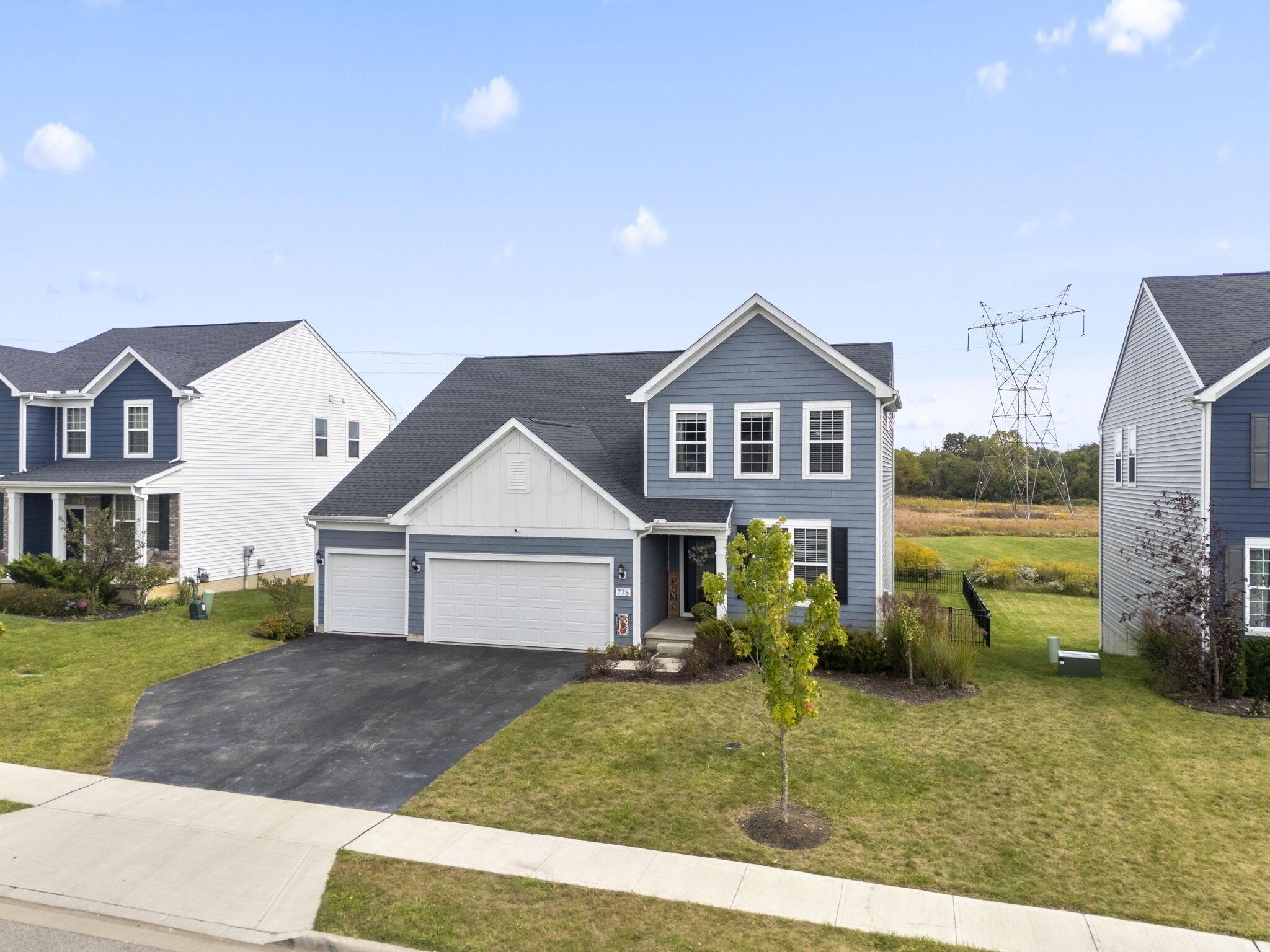 Blue-gray two-story house with white trim, attached two-car garage, and paved driveway.