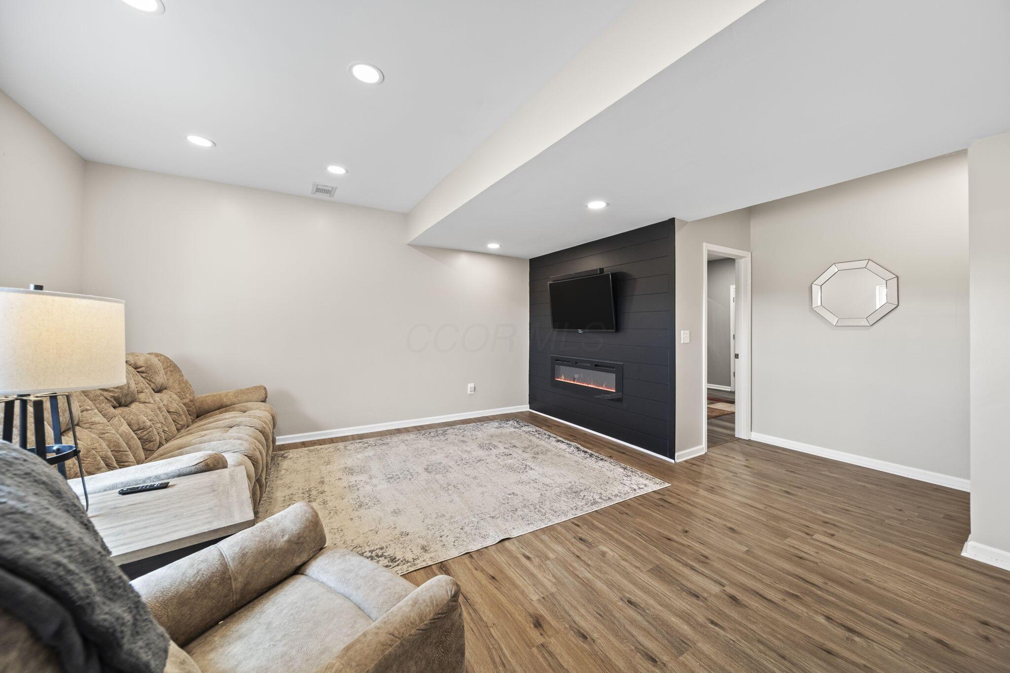 Living room with a black shiplap fireplace wall, wall-mounted television, and neutral seating.