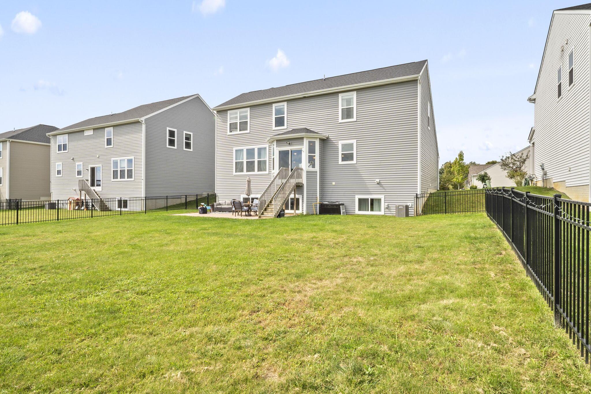 Gray two-story home with a raised deck and fenced grassy backyard.