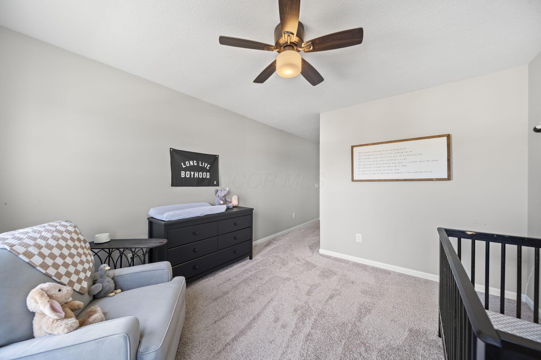 Upstairs landing with a dresser, stuffed animals, ceiling fan, and black stair railing.