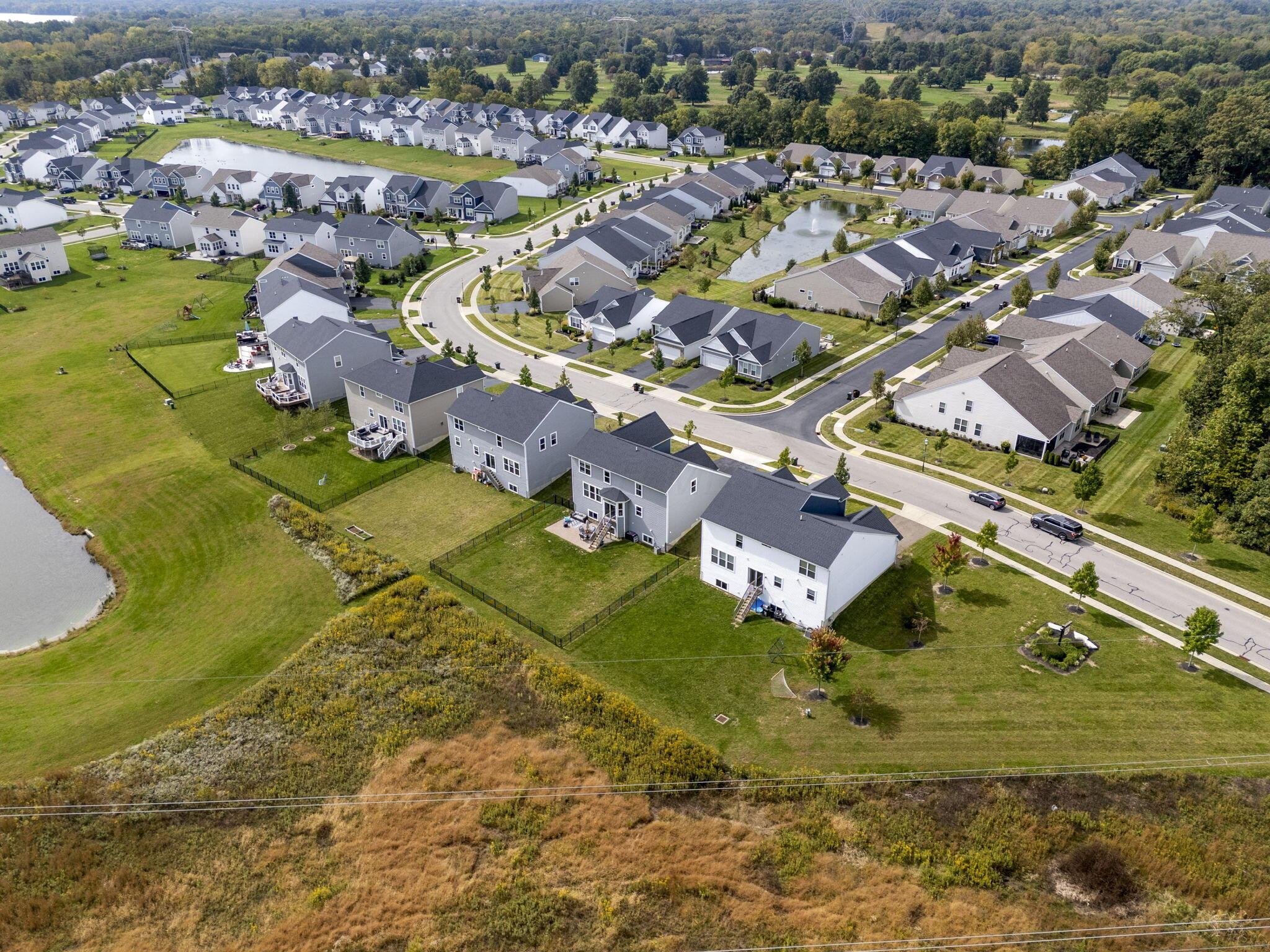 Aerial view of a residential neighborhood with detached homes, curving streets, and ponds.