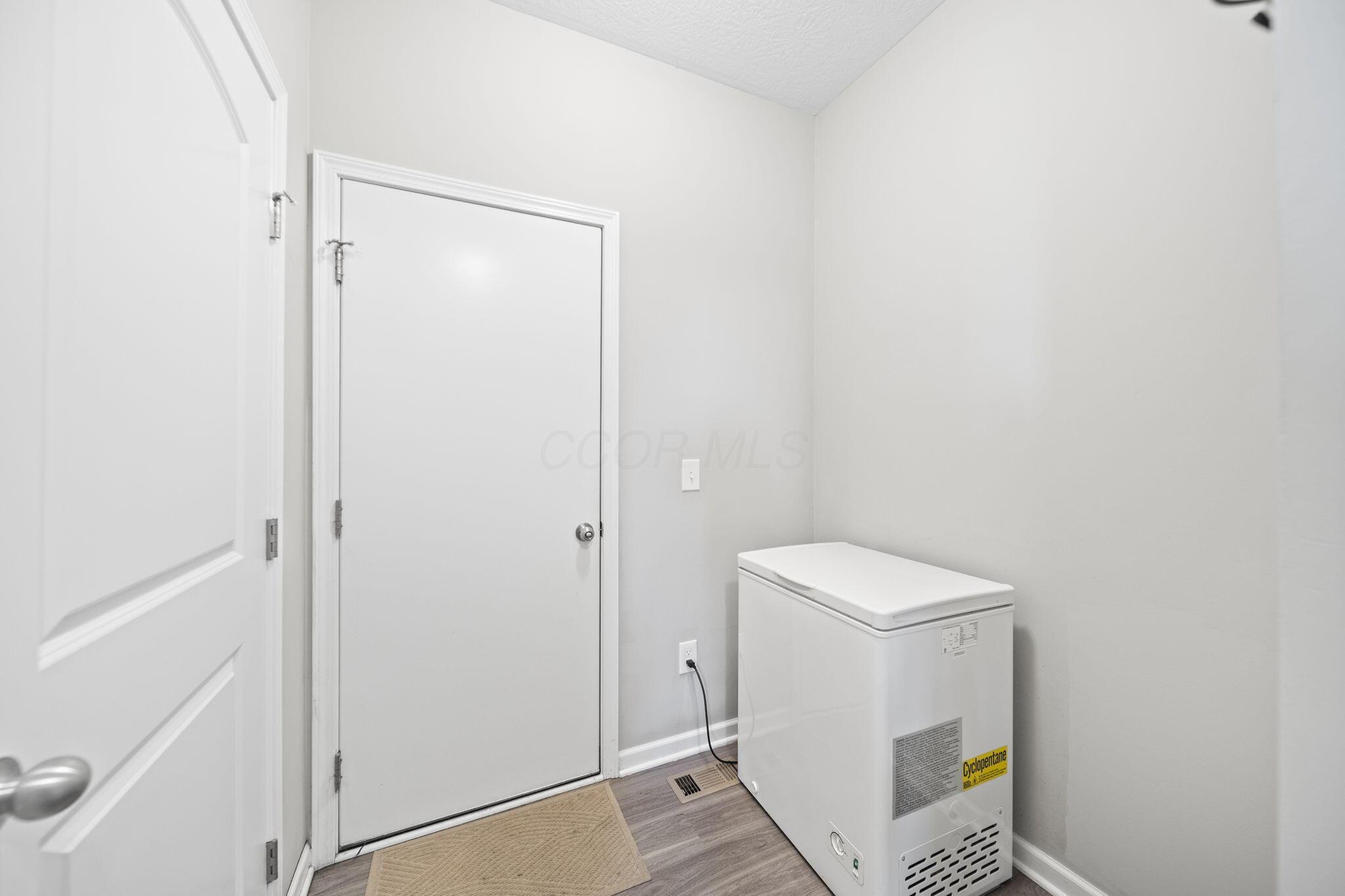 Utility room with a white chest freezer, gray plank flooring, and two closed doors.