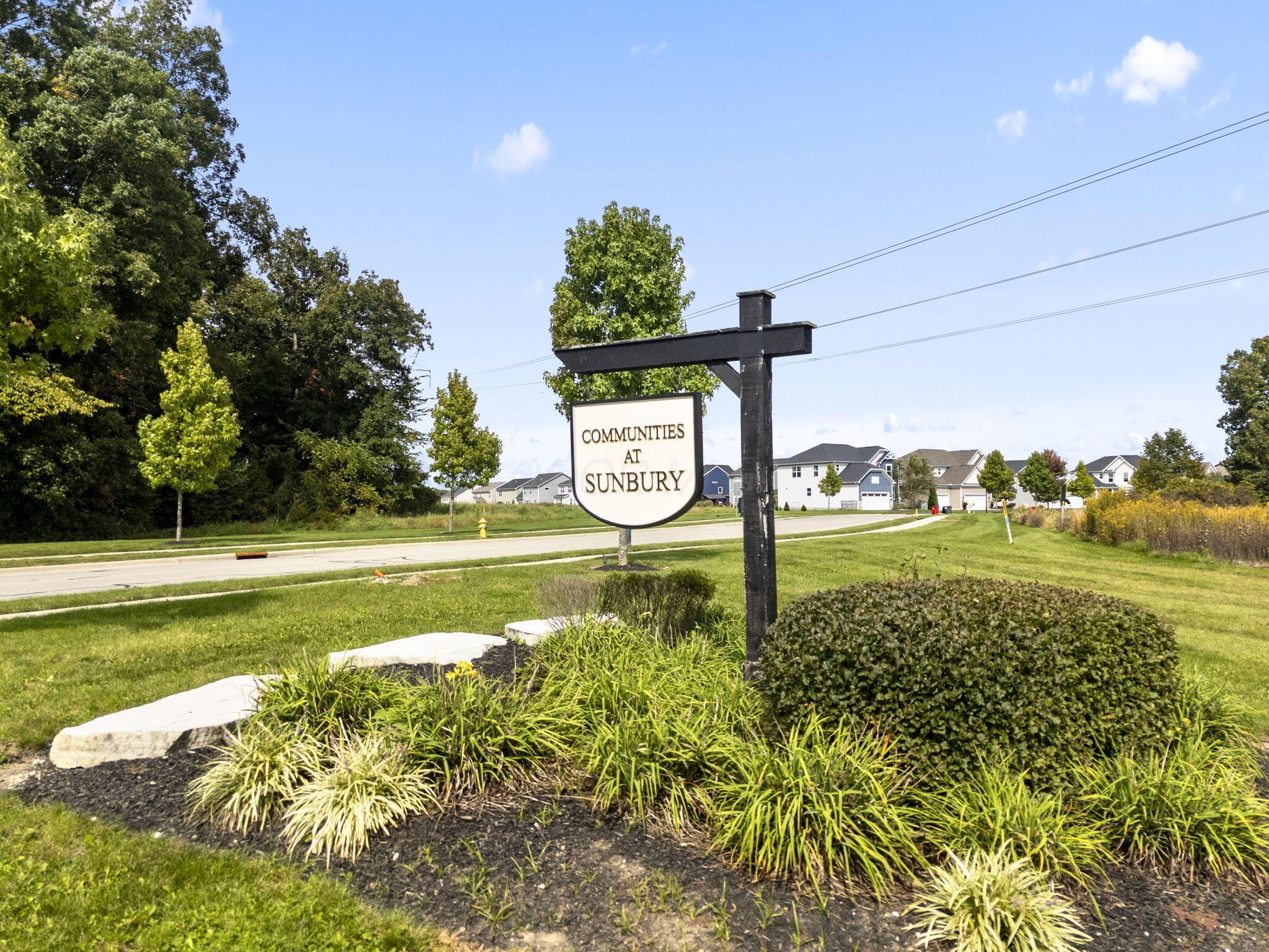 Communities at Sunbury entrance sign beside landscaped beds and neighborhood homes.