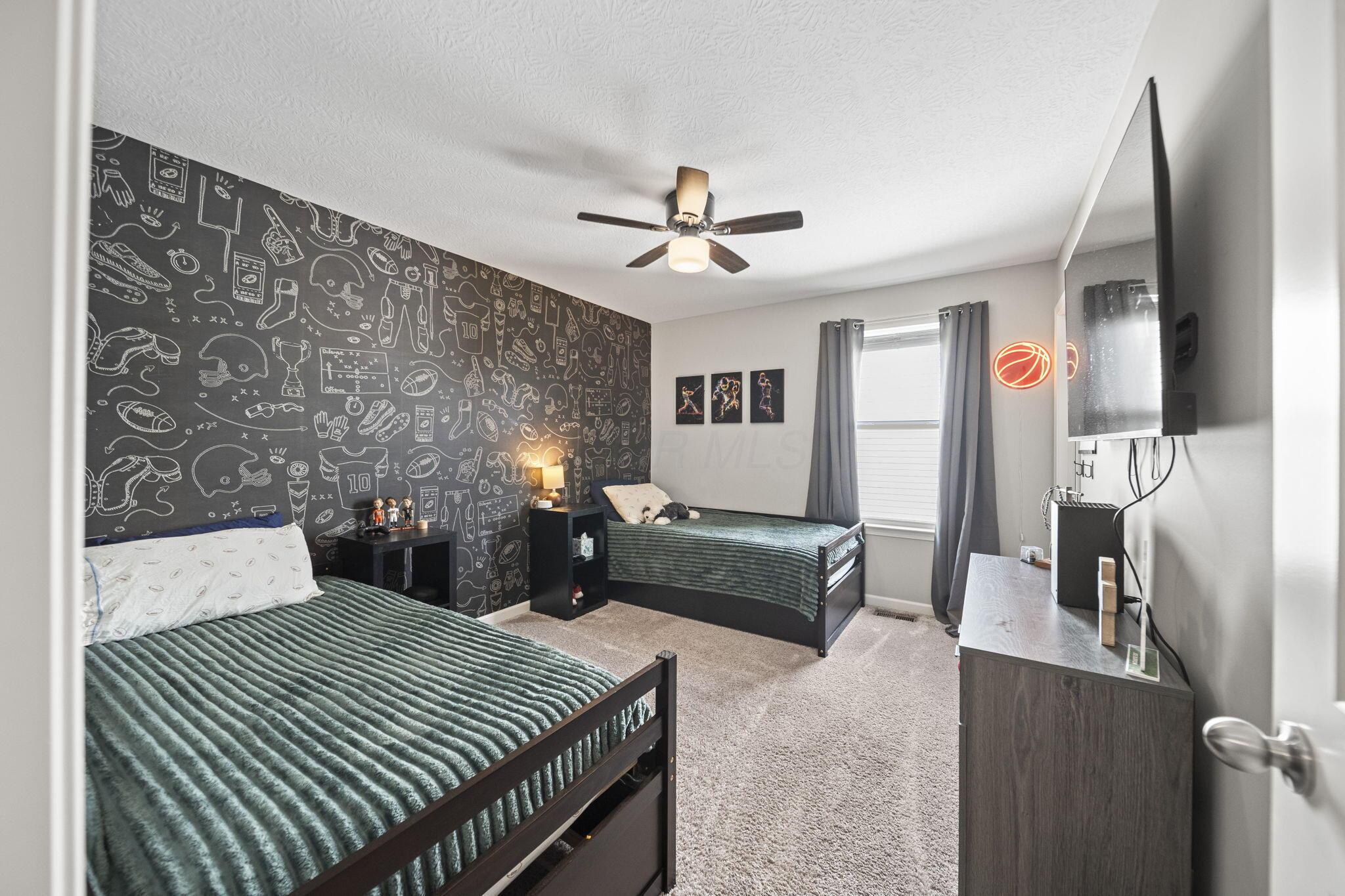 Bedroom with two twin beds, sports-themed wallpaper, and a glowing basketball light.