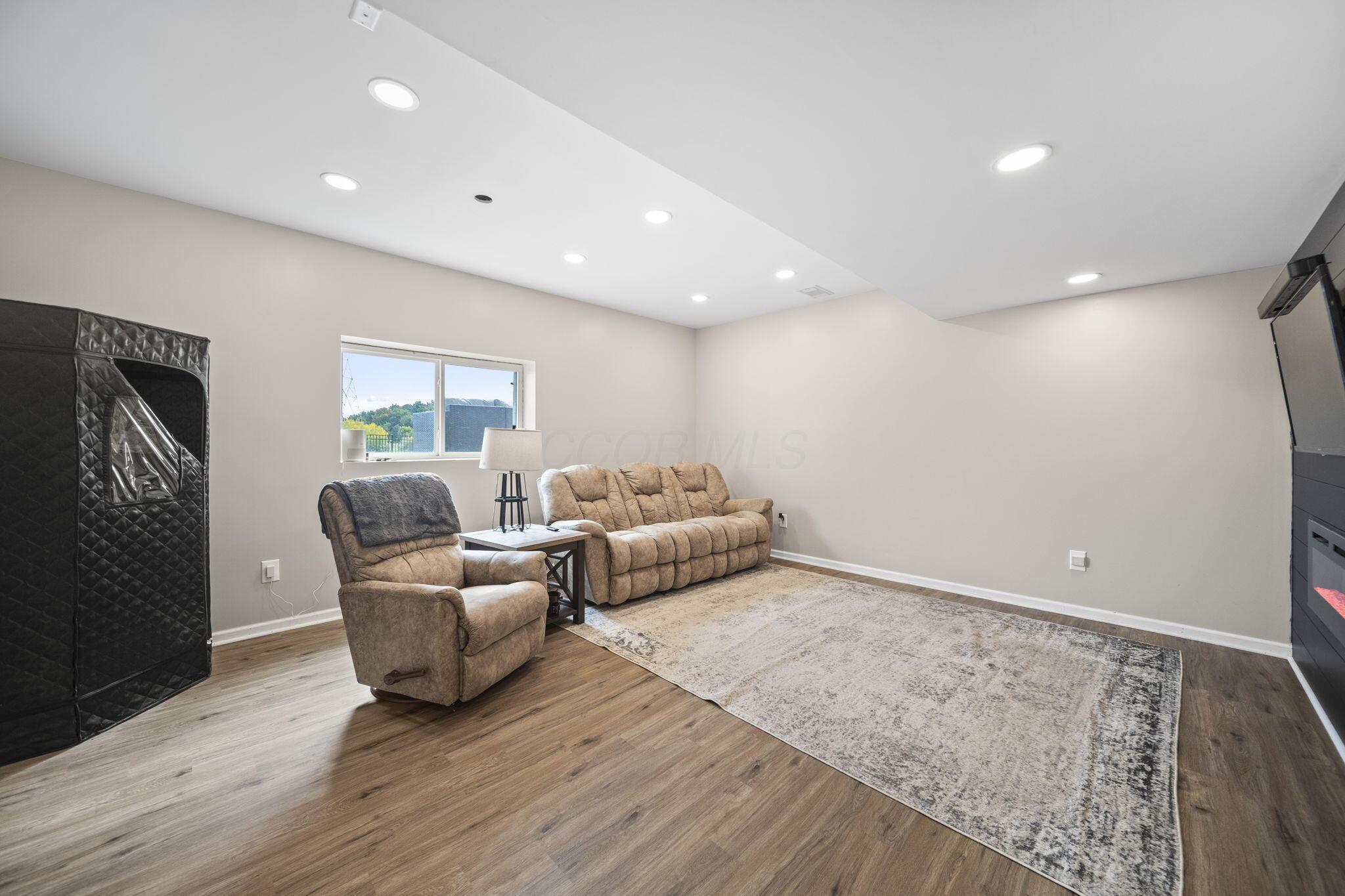 Media room with tan reclining seating, a large patterned rug, and recessed lighting.