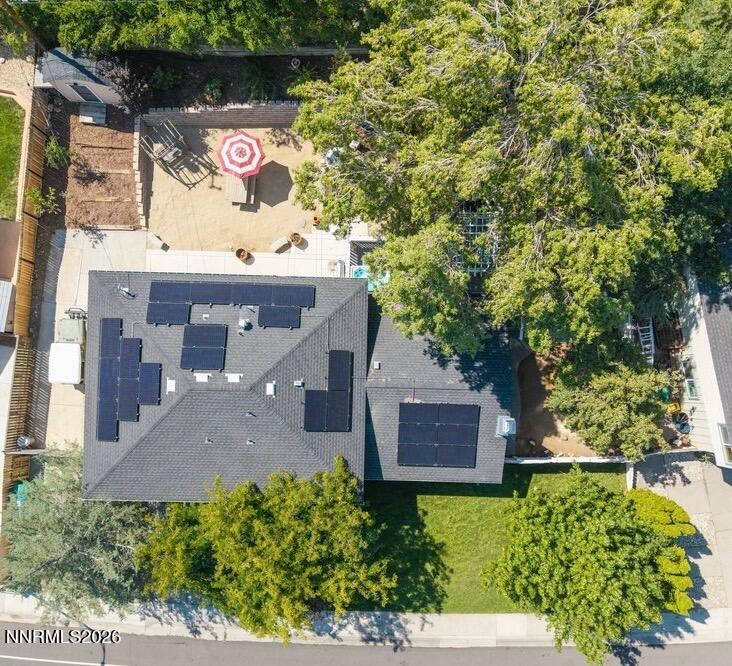 Aerial view of a home with rooftop solar panels and a tree-shaded patio.